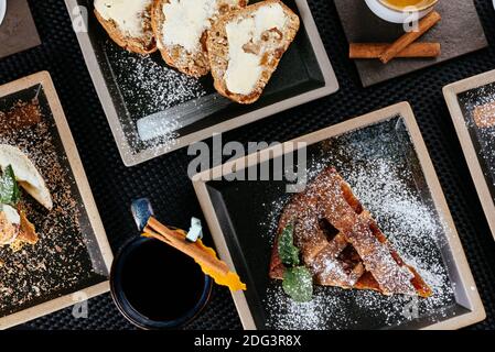 Verschiedene Desserts mit Tee auf schwarzem Hintergrund Stockfoto