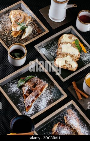 Verschiedene Desserts mit Tee auf schwarzem Hintergrund Stockfoto