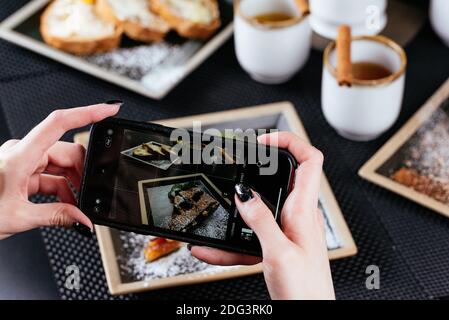 Frauenhände fotografieren Essen am Telefon Stockfoto