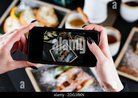 Frauenhände fotografieren Essen am Telefon Stockfoto