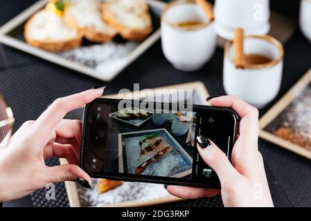 Frauenhände fotografieren Essen am Telefon Stockfoto