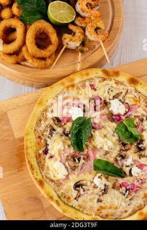 Italienische Pizza und Bier Snacks auf einem Holzbrett und Heller Hintergrund Stockfoto