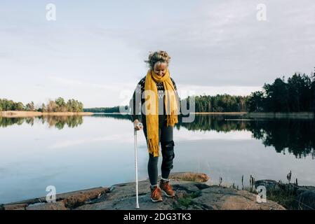 Verletzte Frau, die in Schweden mit Krücken auf den Felsen läuft Stockfoto