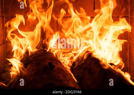 Glühendes Feuer in einem riesigen Steinkamin. Textur der Feuerflamme. Abstrakt brennende Flammen Flammen für Banner Hintergrund. Blaze Feuer für Banner. Brennen Stockfoto