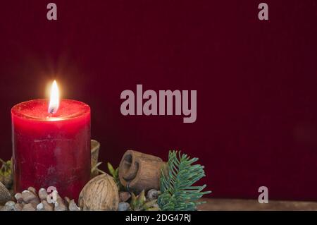 Hintergrund Weihnachtsdekoration, rote Kerze mit Kerzenlicht vor rotem Samt und Kopierraum. Stockfoto