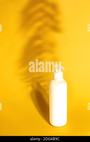 Weiße Pumpe Plastikflasche Mockup gelben Hintergrund mit Schatten Farn Blätter. Spender Flasche, Shampoo Mock up. Branding, Etiketten und Verpackungen Stockfoto