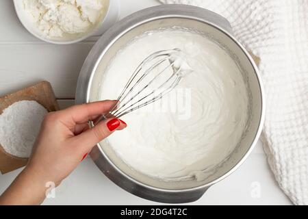 Schritt-für-Schritt-Rezept für herzförmige Kuchen. Schritt 7, Sahne: Die Sahne mit 0,5 Puderzucker verquirlen, den Rest des Pulvers und Ricotta hinzugeben. Fl Stockfoto