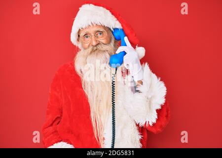 Alter älterer Mann trägt weihnachtsmann Kostüm mit Vintage-Telefon Schauen positiv und glücklich stehen und lächeln mit einem selbstbewussten Lächeln zeigt Teet Stockfoto