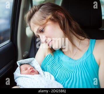 Frau hält neugeborenes Baby im Auto sitzend Stockfoto