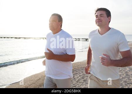 Zwei Männer, die entlang der Küste in hellem Sonnenlicht Stockfoto