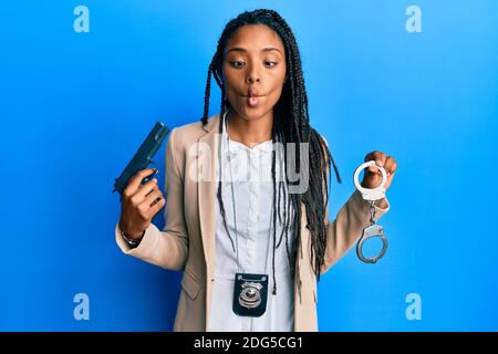 afroamerikanische Polizeifrau, die Gewehr und Handschellen hält und Fische mit Mund und Augen zuckt, verrückt und komisch. Stockfoto