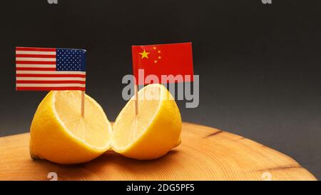 US-amerikanische und chinesische Flaggen, die aus einer aufgeschnittenen Flagge stossen Zitrone auf einem Hackblock, der die angespannte seelengeschüpfte Beziehung darstellt Und Handelskrieg, der geführt wird Stockfoto