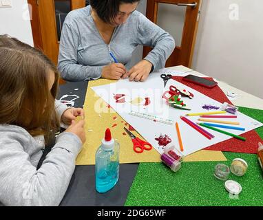 Seitenansicht der Hände einer Frau und einer Mädchen tun Handwerk und Schneiden mit einer Schere auf die Tisch zu Hause Stockfoto
