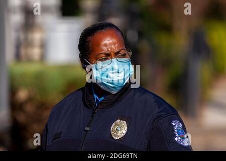 Alexandria, VA, USA 11-28-2020: Ein afroamerikanischer Polizist, der in der Parkplatzbehörde arbeitet, ist im Freien im Dienst. Trägt Gesichtsmaske Stockfoto