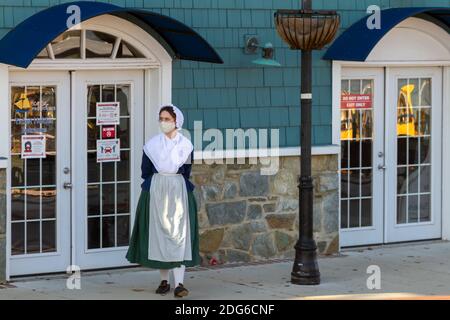 Alexandria, VA, USA 11-28-2020: Eine Restaurantangestellte mit einem kolonialen Frauenkostüm und einer Gesichtsmaske aufgrund von COVID-19 wartet auf den Stockfoto