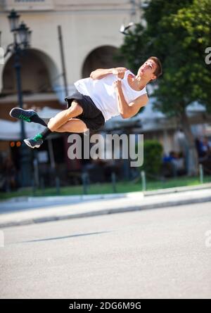 Junger Mann, der auf der Straße einen Salto spielt Stockfoto