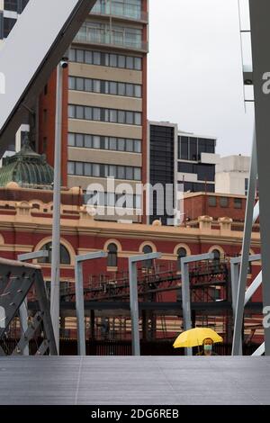 Melbourne, Australien, 14. August 2020. Ein Mann, der eine Maske trägt und unter einem Regenschirm vor Regen schützt, geht während der COVID-19 in Melbourne, Australien, über die Evan Walker Bridge. Victoria hat 14 COVID-bezogene Todesfälle registriert, darunter ein 20-jähriger, der jüngste, der in Australien an Coronavirus starb, und weitere 372 neue Fälle über Nacht.Quelle: Dave Hewison/Alamy Live News Stockfoto