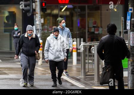 Melbourne, Australien, 14. August 2020. Melbourne Einheimische mit Masken unter ihren Chins gehen während der COVID-19 in Melbourne, Australien, über eine Kreuzung im CBD. Victoria hat 14 COVID-bezogene Todesfälle registriert, darunter ein 20-jähriger, der jüngste, der in Australien an Coronavirus starb, und weitere 372 neue Fälle über Nacht.Quelle: Dave Hewison/Alamy Live News Stockfoto