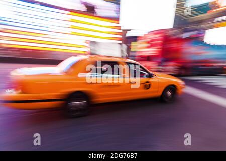 Bild mit Bewegungsunschärfe eines gelben Taxis am Times Square, New York City, in der Nacht Stockfoto