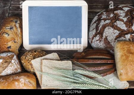 Verschiedene Arten des Brotes mit der Tafel auf hölzern Tabelle Stockfoto