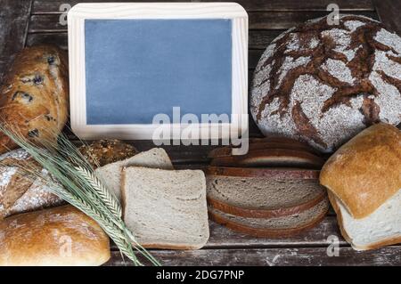 Verschiedene Arten des Brotes mit der Tafel auf hölzern Tabelle Stockfoto