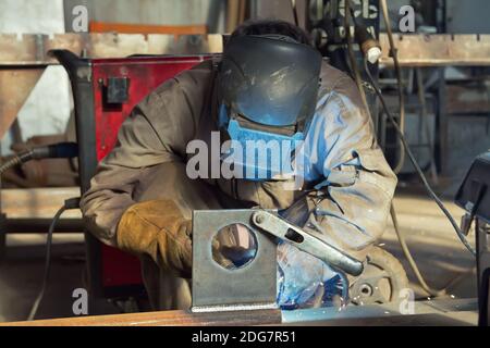 Schweißer in der Maske und Schutzkleidung nimmt zu Verkleidungen Schweißnaht Stockfoto