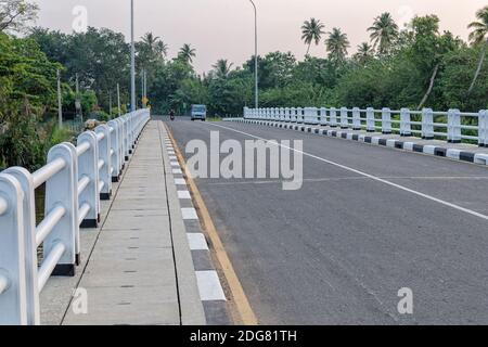 Blick auf die Asphaltbrücke im tropischen Land. Fußgängerweg aus Betonplatten auf der Brücke. Weligama, Sri Lanka Stockfoto