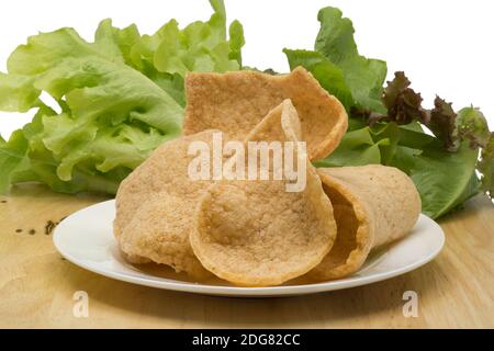 Garnelencracker und Gemüse in einem weißen Teller auf einem Holzbrett Stockfoto