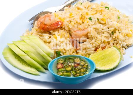 Gebratener Reis mit Garnelen, Ei, Gurke, Chili, Fischsauce und Zitrusfrüchten auf einem blauen Teller Stockfoto