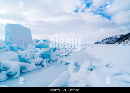 Reihe von Eisblöcken und der Berg bedeckt mit Schnee Am Baikalsee Stockfoto