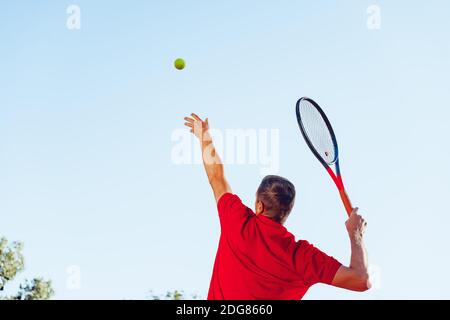 Junger professioneller Tennisspieler, der einen Service leistet Stockfoto