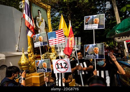 Bangkok, Thailand. Dezember 2020. Pro-demokratische Anhänger halten fotoshopped Zeichen, die Joe Biden hält die drei Finger Salut und eine Warnung, nicht zu schaden jungen Demonstranten oder US-Intervention konfrontiert, zur Unterstützung von vier Protestführer, die auf les majeste (Abschnitt 112 des Strafgesetzbuches) vorgeladen Anklage außerhalb der Nonthaburi Polizeiwache in Bangkok, Thailand, am Dienstag, den 08. Dezember 2020. Die Protestführer Parit 'Penguin' Chiwarak, Panupong 'mike'' Jadnok, Panusaya 'rung' Sithijirawattanakul und Chinnawat Chankrachang tauchten auf der Polizeistation auf, um die Majeste zu hören Stockfoto