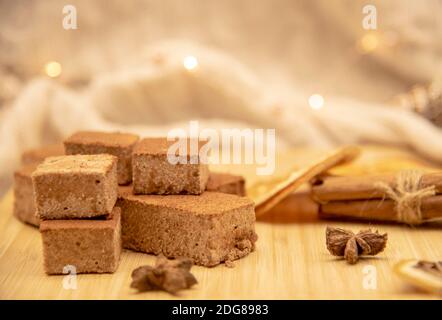 Duftende Gewürze und hausgemachte Marshmallows auf einem Holztablett, mit festlicher Girlande verziert. Stockfoto