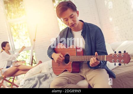 Junge Männer spielen zuhause Gitarre Stockfoto