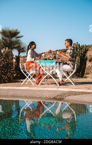 Ehepaar beim Frühstück im Garten mit Blick auf die Hügel von Sizilien, Männer und Frauen mittleren Alters im Urlaub beim Frühstück im Freien Stockfoto