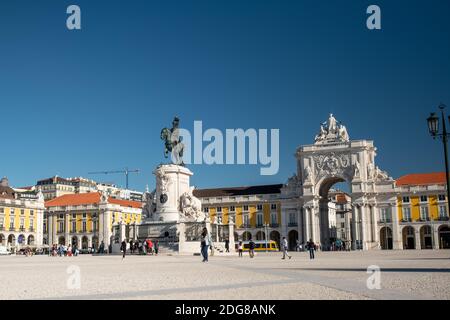 Der Handelsplatz der Rua Augusta Arch und die vorbeiziehenden Menschen in Lissabon. Straßenbahn fährt vor dem Bogen Stockfoto