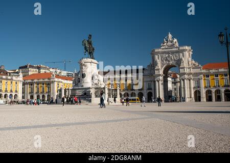 Der Handelsplatz der Rua Augusta Arch und die vorbeiziehenden Menschen in Lissabon. Straßenbahn fährt vor dem Bogen Stockfoto