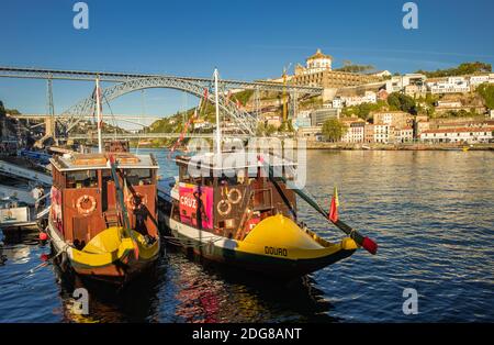 Zwei Ausflugsboote, die am Ufer des Douro-Flusses in Ribeira in Porto, Portugal, festgemacht wurden. Luís i Bridge ist im Hintergrund Stockfoto