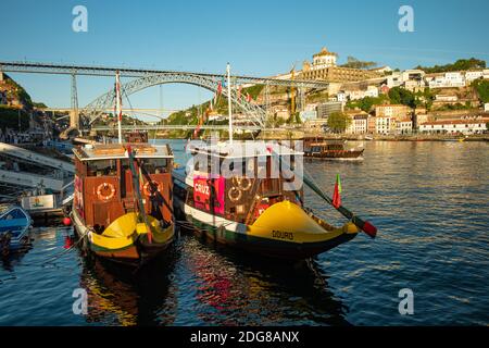 Zwei Ausflugsboote, die am Ufer des Douro-Flusses in Ribeira in Porto, Portugal, festgemacht wurden. Luís i Bridge ist im Hintergrund Stockfoto