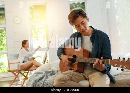 Junge Männer spielen zuhause Gitarre Stockfoto