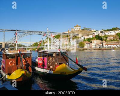 Zwei Ausflugsboote, die am Ufer des Douro-Flusses in Ribeira in Porto, Portugal, festgemacht wurden. Luís i Bridge ist im Hintergrund Stockfoto