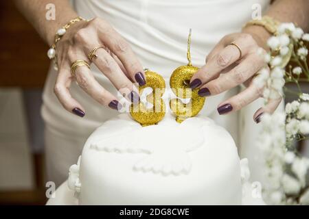Nahaufnahme einer Frau, die die Nummer aufsetzt 39 Kerzen auf einem Kuchen Stockfoto