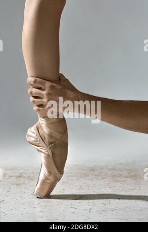 Guy hält Ballerinas Bein Stockfoto