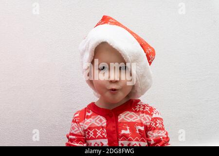 Kleinkind bei Red Santa Hut überrascht und aufgeregt warten Weihnachten Und Neujahr Stockfoto