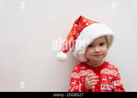 Cute kaukasischen Baby Mädchen in roten Winter Pijamas und rot Weihnachtsmann Hut lächelnd Stockfoto