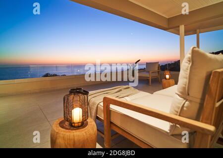 Laterne und Sessel auf Luxus-Terrasse mit malerischen Sonnenuntergang Ozean Anzeigen Stockfoto