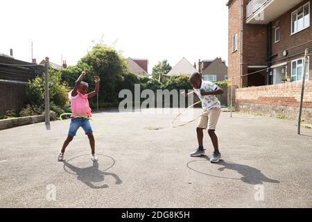 Verspielte Bruder und Schwester spinnen in Kunststoff-Reifen in sonnigen Los Stockfoto