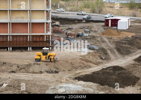 Buldozer Herstellung und Bau neuer Asphaltstraße und Clearing Gebiet in der Nähe von zivilen Gebäude. Die Konzepte der Verbesserung des Territoriums der Gebäude. Stockfoto