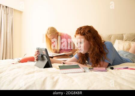 Präteen Mädchen Freunde mit digitalen Tablet Hausaufgaben auf dem Bett zu tun Stockfoto