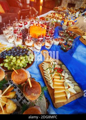 Verschiedene Arten von Vorspeisen am Buffet. Leckeres und Interessantes Essen. Naturkäse wird auf einem Holzbrett getragen Stockfoto